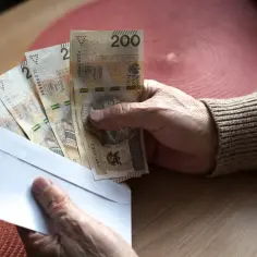 Dłoń trzyma kopertę z banknotami 200 zł. Czy praktyki liczą się do emerytury?