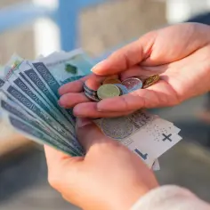 Dłonie liczą banknoty i monety. To może być symbol walki o godne zarobki, gdzie nawet najniższa krajowa netto za godzinę ma znaczenie.