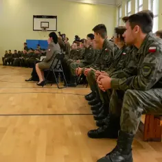 Młodzi ludzie w mundurach siedzą na sali gimnastycznej, słuchając przemówienia. Czy po zawodówce można iść do wojska? Tak, to możliwe!
