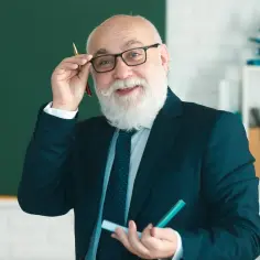 Uśmiechnięty starszy pan w okularach, z białą brodą, trzymający długopis i marker. Zastanawia się, czy zawodówka wlicza się do emerytury.