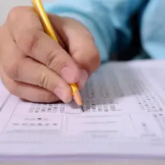 Ręka z ołówkiem zaznacza odpowiedzi na arkuszu testowym. Zastanawiasz się, jaki certyfikat z angielskiego do pracy będzie najlepszy?