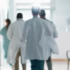 Lekarze w białych fartuchach spieszą korytarzem. Zastanawiasz się, ile zarabia lekarz?