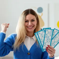 Uśmiechnięta kobieta z kartami do gry w bingo, świętująca wygraną. Zastanawiasz się, dlaczego pracownicy nie mogą brać udziału w loteriach organizowanych przez firmę?