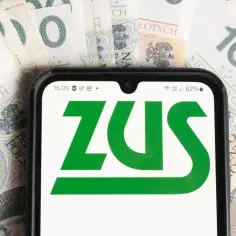 Telefon z logo ZUS na tle banknotów 100 zł. Sprawdź, jak sprawdzić staż pracy w PUE ZUS.