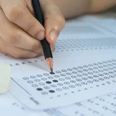 Dłoń z ołówkiem zaznacza odpowiedzi na arkuszu. Zastanawiasz się, ile jest pytań na egzaminie zawodowym?