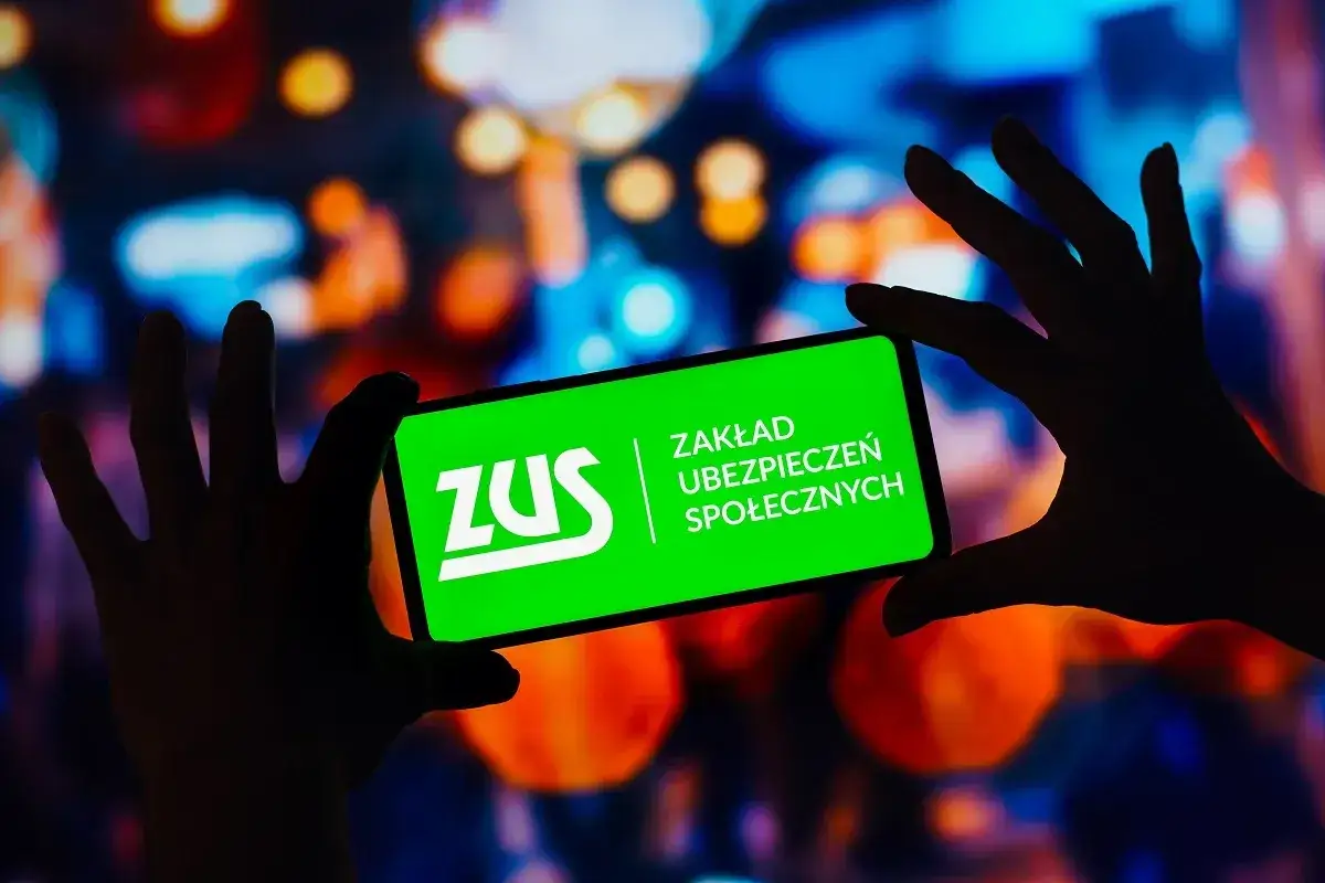 Dłonie trzymają smartfon z zielonym ekranem i logo ZUS. Sprawdź, gdzie sprawdzić ile ma się lat pracy, korzystając z aplikacji ZUS.
