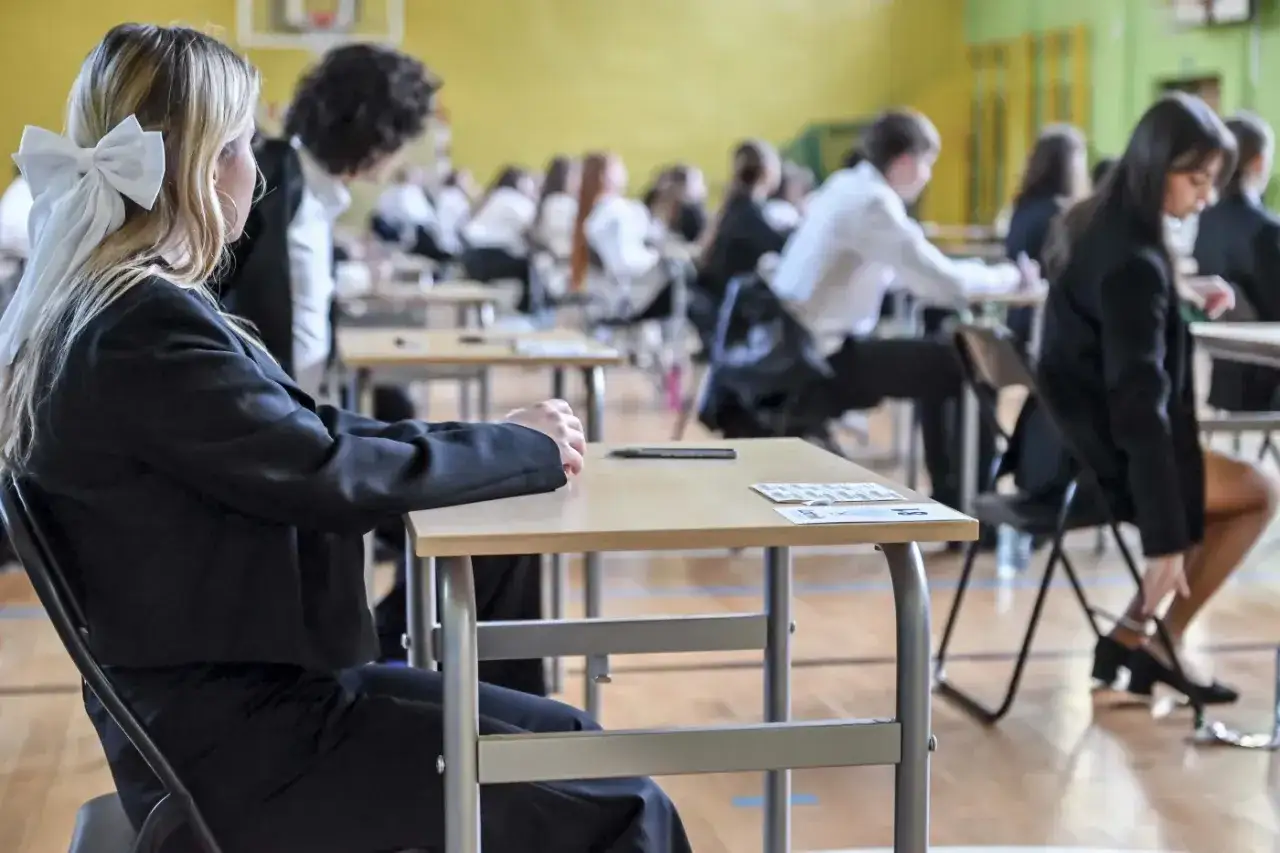 Uczniowie w ławkach, skupieni na egzaminie. To ważny moment, kiedy zawodówka kończy szkołę i zaczyna nowy etap.