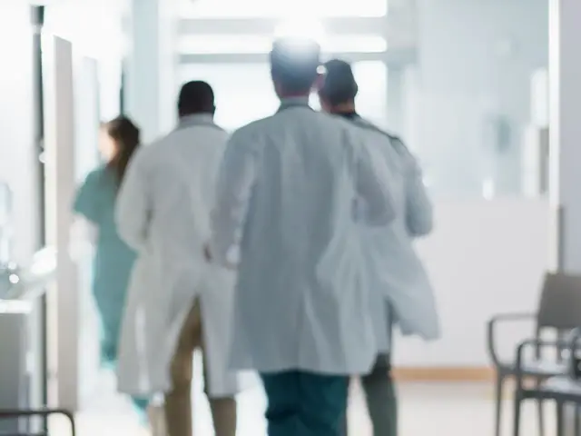 Lekarze w białych fartuchach spieszą korytarzem. Zastanawiasz się, ile zarabia lekarz?